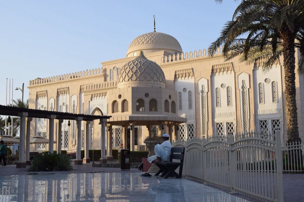 Jumeirah Mosque in Dubai at dusk, with palms alongside its twin domes.